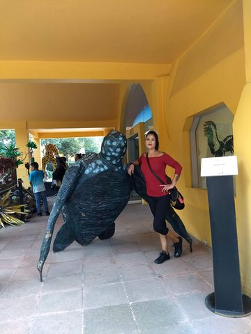 A woman poses next to a large turtle sculpture in a covered walkway. MJ, Polanco, Mexico, August 19, 2018