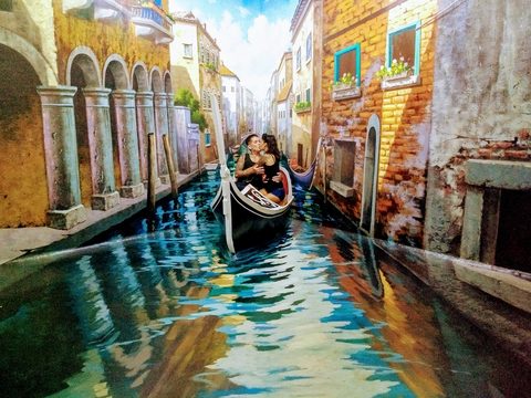 A couple poses for a photo inside a gondola within a realistic canal mural. Cisco, Dream Museum Zone Bali (DMZ), Kuta, Indonesia, February 4, 2018