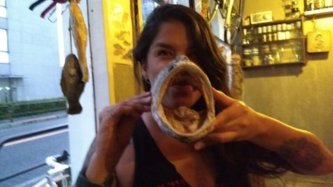 A woman holds up a large, dried fish head in front of her face. MJ, Tokyo, Japan, June 21, 2017