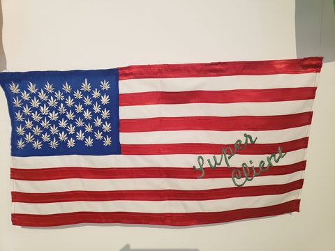 A modified American flag with cannabis leaves in the blue canton and the words 'Super Client' embroidered on the stripes. Museo Textil de Oaxaca, Oaxaca de Juarez, Mexico, October 26, 2019