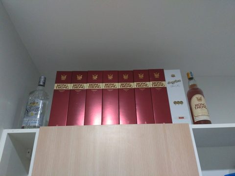 A collection of several red boxes and two bottles of alcohol are arranged on a white shelf. The Mark Ratchada Airport Link, Din Daeng, Thailand, March 16, 2016