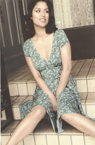 A woman in a patterned dress sits on steps near a building entrance at night. May 16, 2006